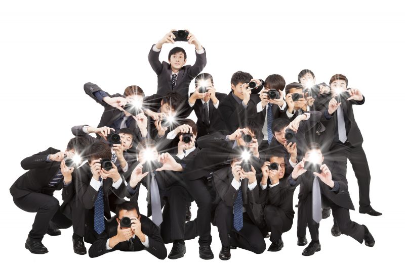 many photograper holding camera pointing to you and isolated on white
